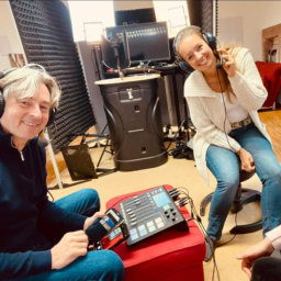 Podcastdrehtag Zwei Personen in einem Aufnahmestudio, lächelnd, mit Kopfhörern und Equipment.